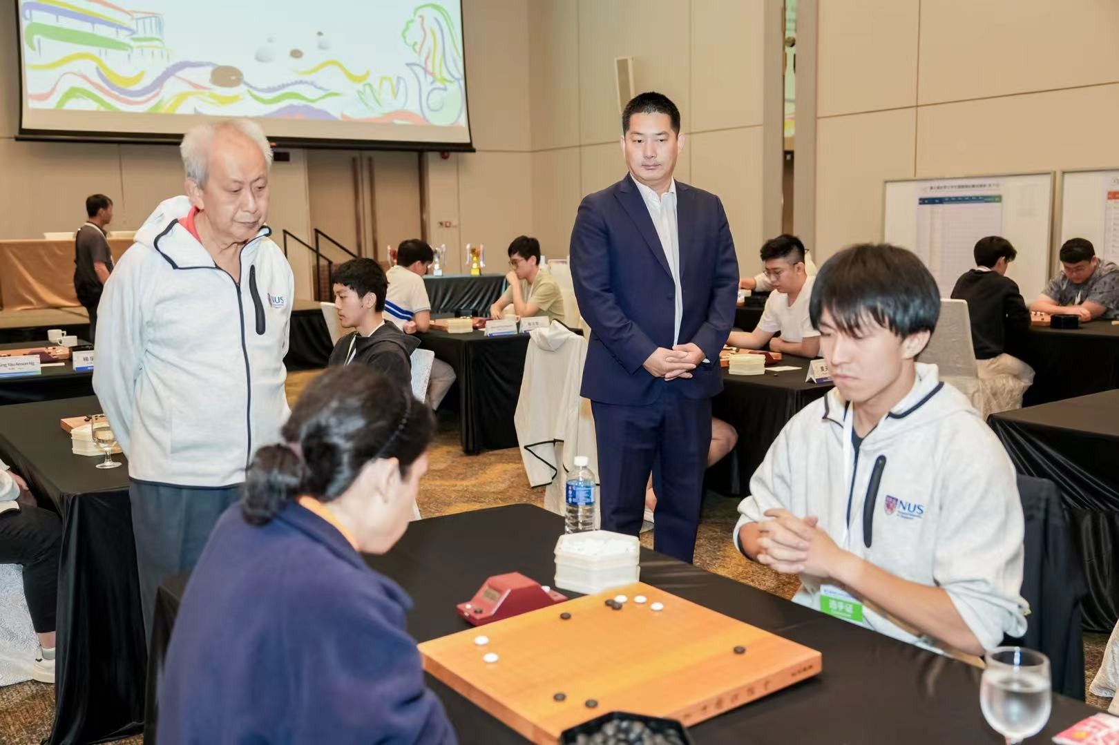 中(zhōng)国(guó)围(wéi)棋(qí)协(xié)会(huì)主席(xí)常(cháng)昊(hào)（右(yòu)二(èr)）、新(xīn)加(jiā)坡(pō)围(wéi)棋(qí)协(xié)会(huì)会(huì)长(zhǎng)陈(chén)丁(dīng)川(chuān)（左(zuǒ)一(yī)）观(guān)战(zhàn)。中(zhōng)国(guó)围(wéi)棋(qí)协(xié)会(huì)供(gōng)图(tú)